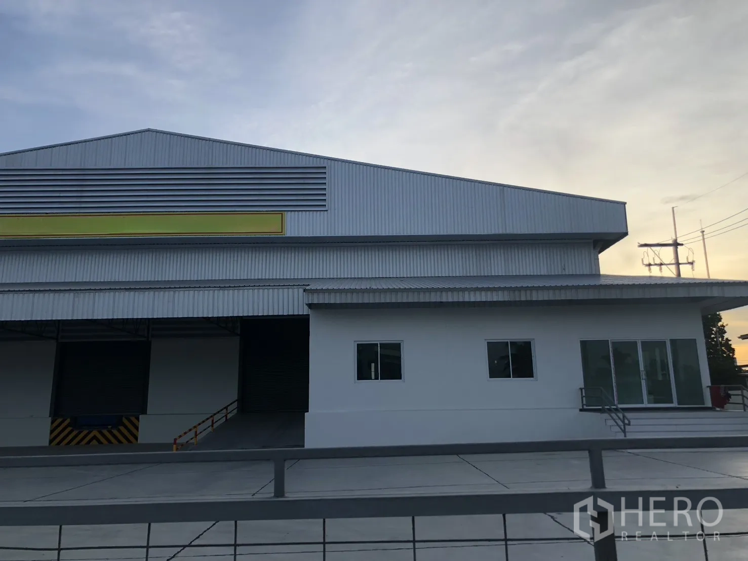 Factory for rent in Si Racha, Chon Buri - Modern factory exterior with roller shutter doors and a large paved frontage.