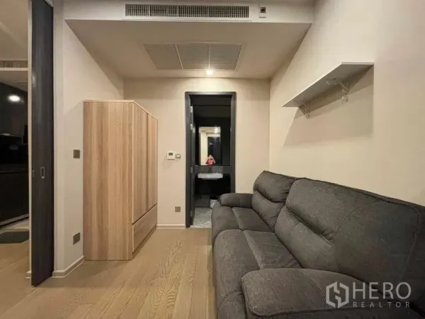 คอนโด ให้เช่าในWatthana, Bangkok - มุมนั่งเล่นโซฟาผ้าสีเทา ตู้เสื้อผ้า และมองไปยังห้องน้ำสไตล์โมเดิร์น