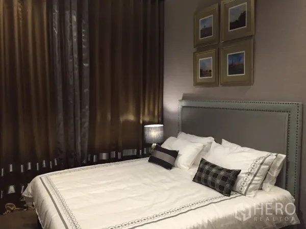 Condominium for rent in Bang Rak, Bangkok - Spacious master bedroom with padded headboard, large bed, and floor-to-ceiling blackout curtains with wall art.