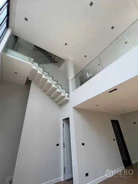 Home Office for sale in Wang Thonglang, Bangkok - Bright interior showing a staircase with glass balustrade and high ceiling in an open-plan space.
