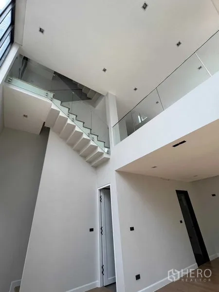 Home Office for sale in Wang Thonglang, Bangkok - Bright interior showing a staircase with glass balustrade and high ceiling in an open-plan space.