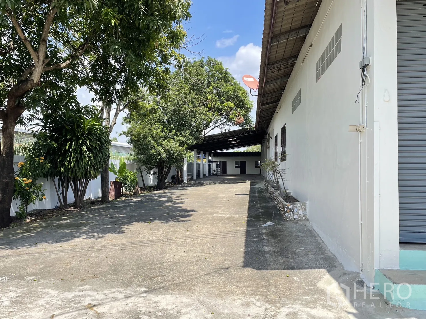 工厂 出租或出售在Pathum Thani - 白色厂房旁的长车道，屋顶装有卫星天线。