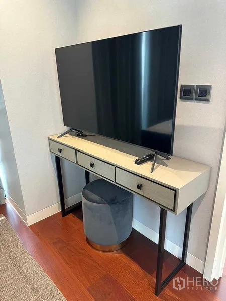 公寓 出租在Watthana, Bangkok - 现代客厅内的纤薄电视柜与电视，旁有圆凳。