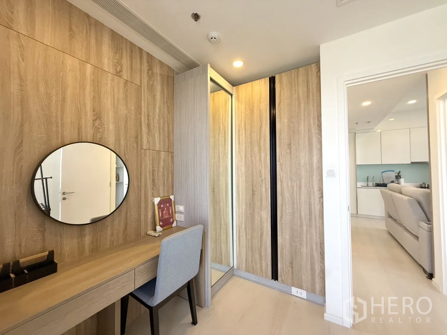 Condominium for sale in Chatuchak, Bangkok - Dressing area with wooden desk, round mirror, and wardrobes.