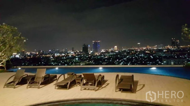 Condominium for rent in Bang Kho Laem, Bangkok - Rooftop pool deck at night with loungers and wide city views.