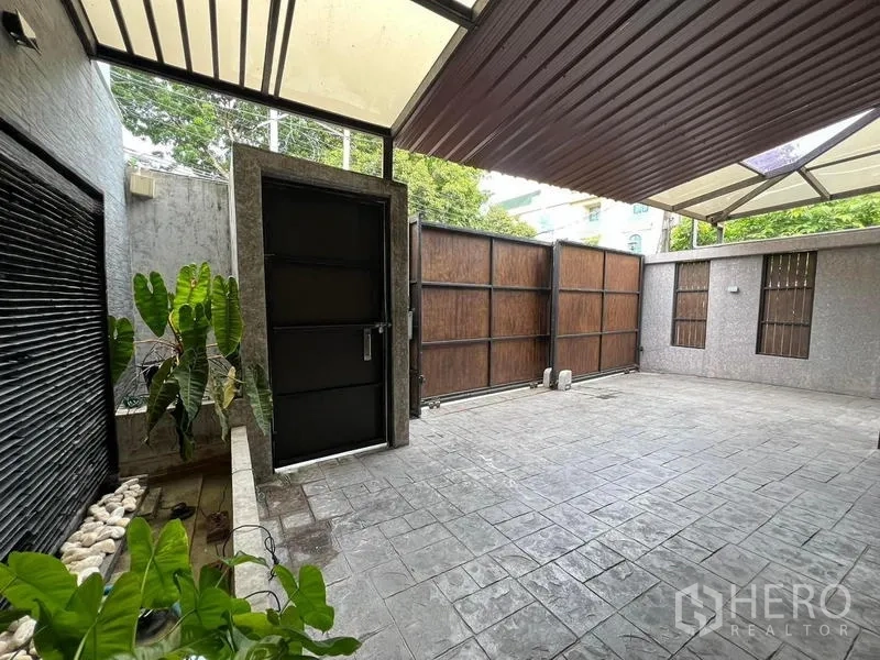 Townhouse for rent in Phaya Thai, Bangkok - Covered carport with tiled driveway and tall wooden gates for secure parking.