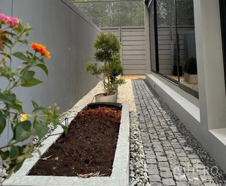 联排别墅 出售在Lat Phrao, Bangkok - 侧院狭长花圃与卵石步道，私密围栏。