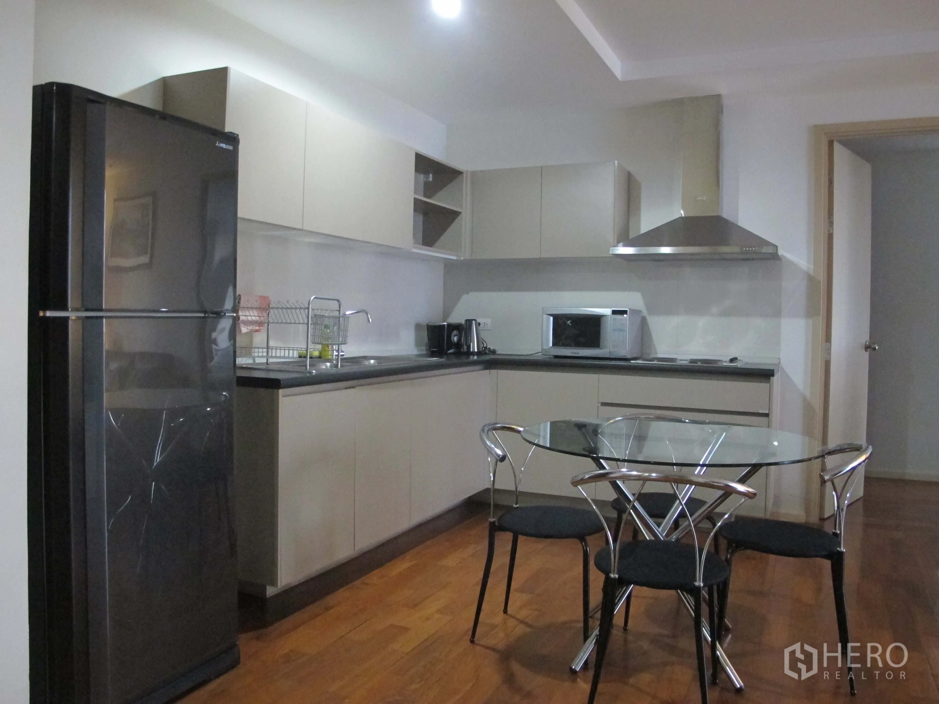公寓 出租在Khlong Toei, Bangkok - 开放式厨房，内置橱柜、玻璃餐桌、冰箱与抽油烟机，木地板。