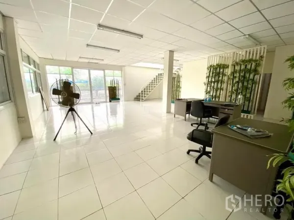 Warehouse for rent in Lam Luk Ka, Pathum Thani - Bright tiled office area with large windows, desks and a staircase inside the warehouse building.