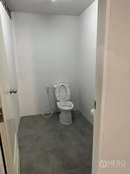 Warehouse for rent in Pak Kret, Nonthaburi - Clean staff toilet with tiled floor and handheld bidet spray.