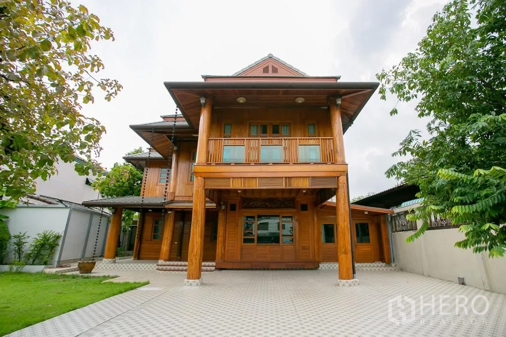 Detached House for rent or sale in Huai Khwang, Bangkok - Front elevation with tall wooden columns and a large paved forecourt.