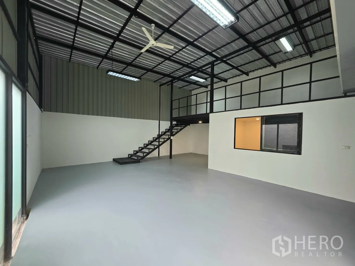 Warehouse for rent in Suan Luang, Bangkok - Open-plan warehouse interior with mezzanine, stairs, and overhead lighting.
