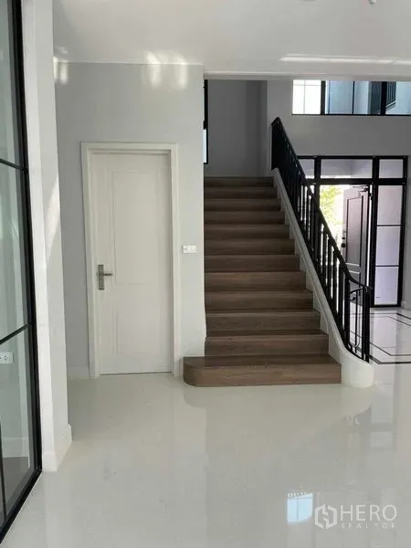 Detached House for sale in Saphan Sung, Bangkok - Bright entry with wooden staircase and white door in a modern detached house.