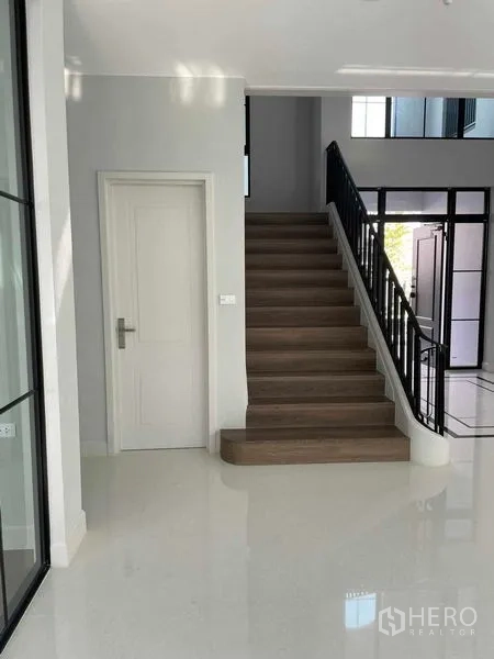 Detached House for sale in Saphan Sung, Bangkok - Bright entry with wooden staircase and white door in a modern detached house.