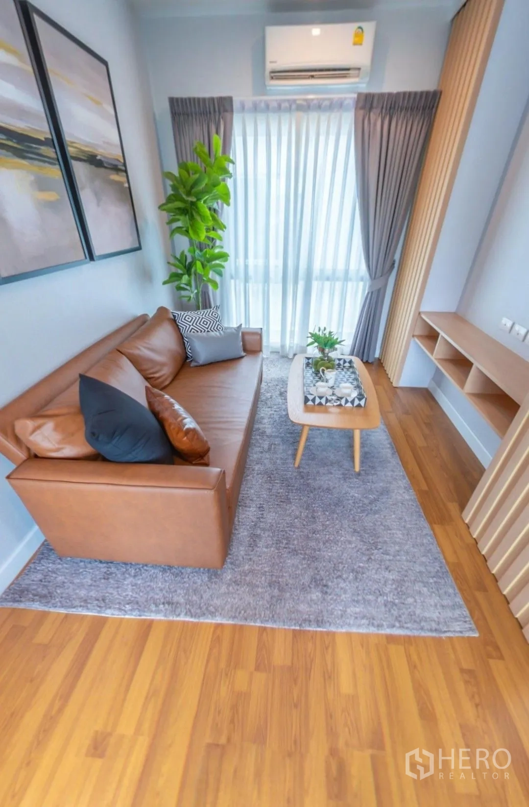 独栋房屋 for rent in Lam Luk Ka, Pathum Thani - 小型家庭休闲区，皮沙发、茶几、绿植与纱帘。