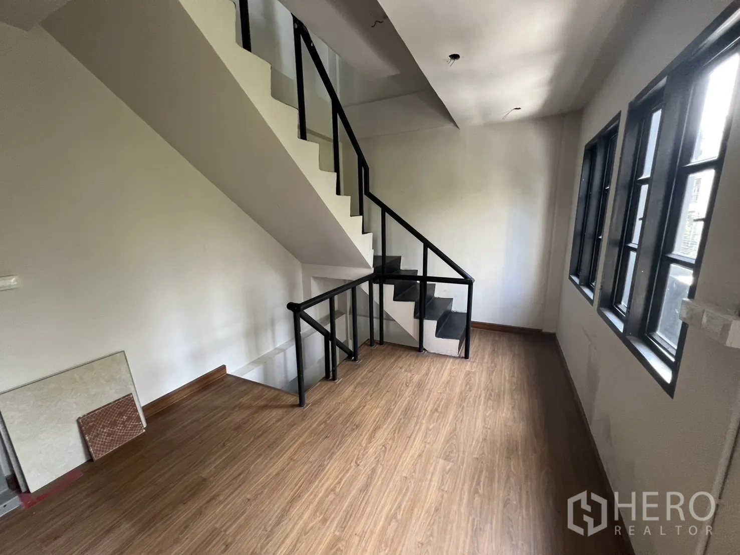 店屋 出租在Watthana, Bangkok - 楼梯间木质地面与黑色金属扶手，旁有窗户。