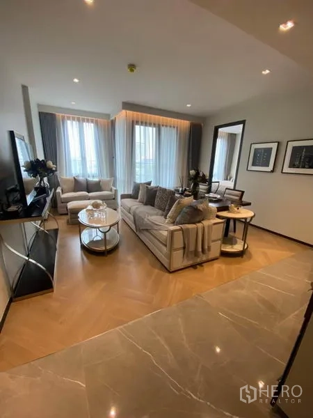 Condominium for rent in Watthana, Bangkok - Bright living room with corner windows, sofas and TV console in a modern Bangkok condominium.