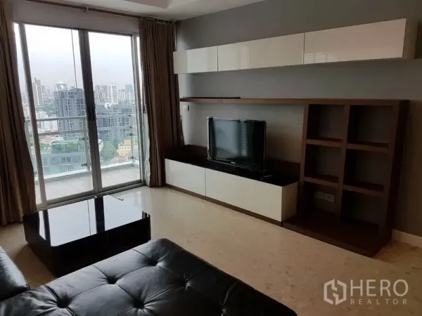 คอนโด ให้เช่าในKhlong Toei, Bangkok - ห้องนั่งเล่นสว่างพร้อมโซฟาหนัง ชุดทีวีบิลท์อิน และประตูกระจกสไลด์เปิดสู่ระเบียงชมวิวเมืองกรุงเทพฯ