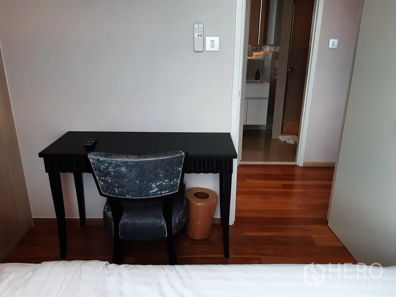 Condominium for rent in Watthana, Bangkok - Bedroom study corner with a black desk and chair facing the bathroom entrance.