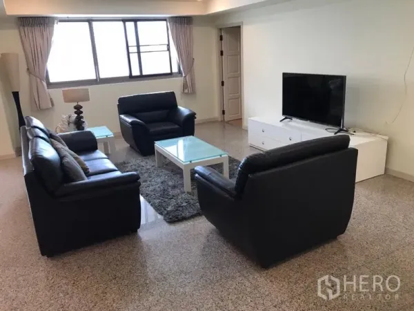 Condominium for rent in Watthana, Bangkok - Bright living room with black leather sofas, TV console and large windows.