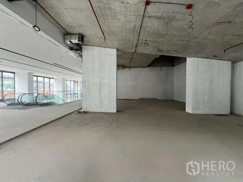 零售空间 出租 - 靠近扶梯与落地窗的开放式商铺，未完成的混凝土顶与结构立柱