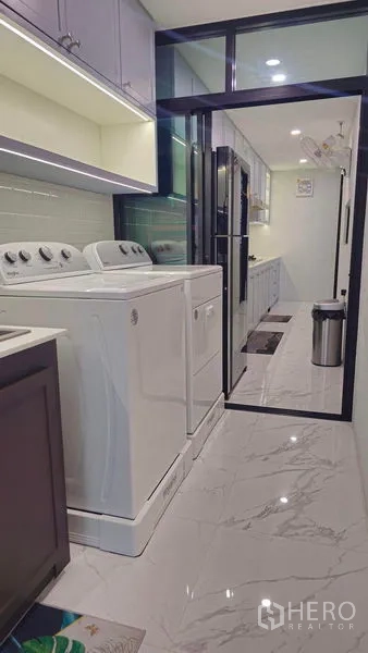 独立式住宅 出售在Sai Mai, Bangkok - 洗衣房配洗衣机和烘干机，旁有推拉玻璃门通向厨房。