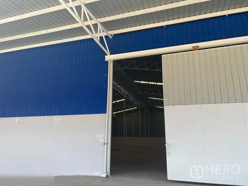 Warehouse for rent in Lat Krabang, Bangkok - Blue-and-white sliding steel warehouse door with covered entry.