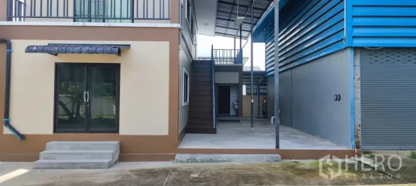 Warehouse for sale in Thung Khru, Bangkok - Covered walkway between office block and warehouse with stairs and roller door.