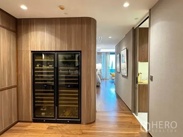 公寓 出售在Khlong Toei, Bangkok - 走廊带弧形木饰面与内嵌双开酒柜，通向客厅。