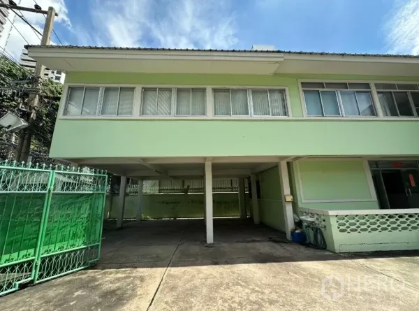 零售空间 出租在Watthana, Bangkok - 正立面，二层下方车棚与绿色金属大门。