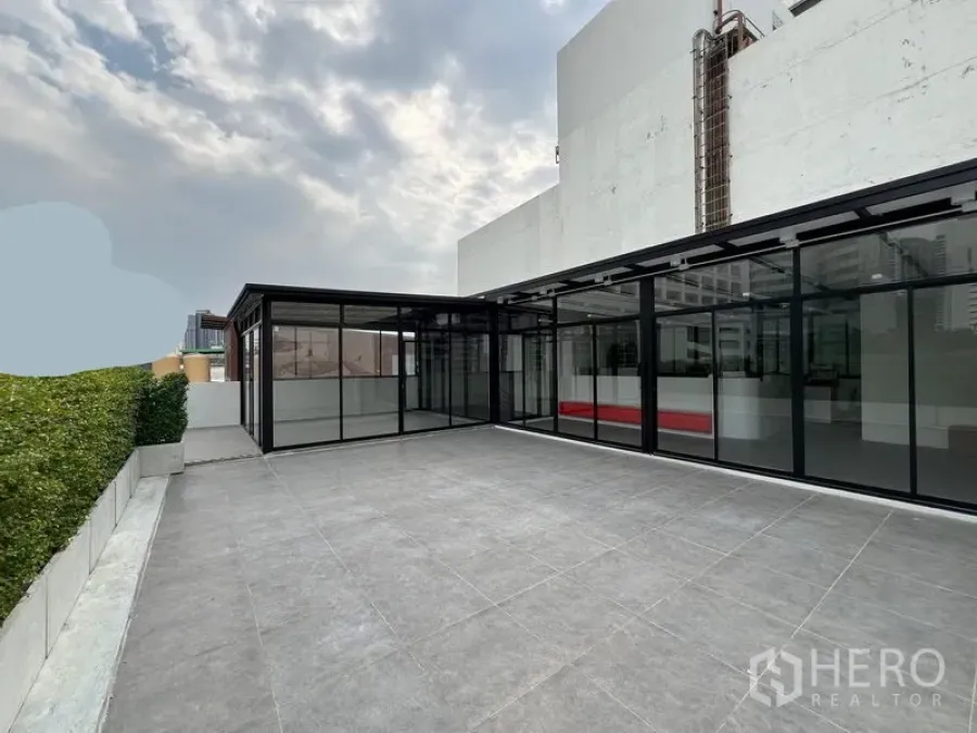 พื้นที่ขายปลีก ให้เช่าในWatthana, Bangkok - ลานกระเบื้องกว้างบนดาดฟ้า ข้างอาคารค้าปลีกกระจกสมัยใหม่.