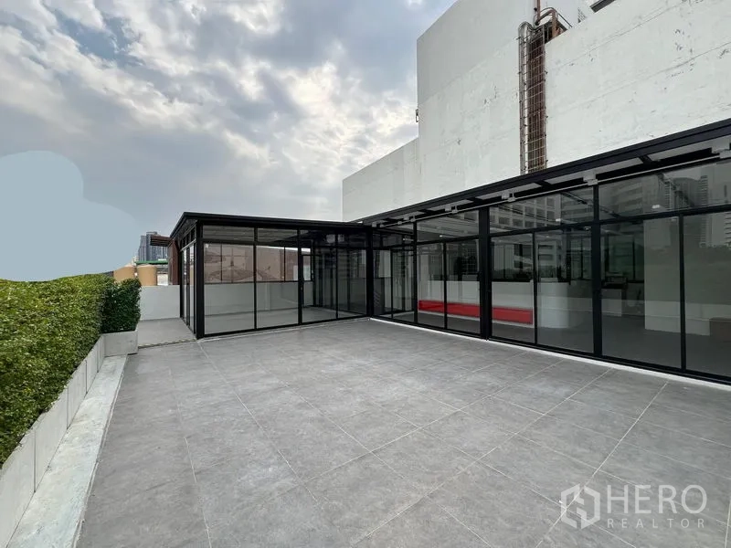 พื้นที่ขายปลีก ให้เช่าในWatthana, Bangkok - ลานกระเบื้องกว้างบนดาดฟ้า ข้างอาคารค้าปลีกกระจกสมัยใหม่.