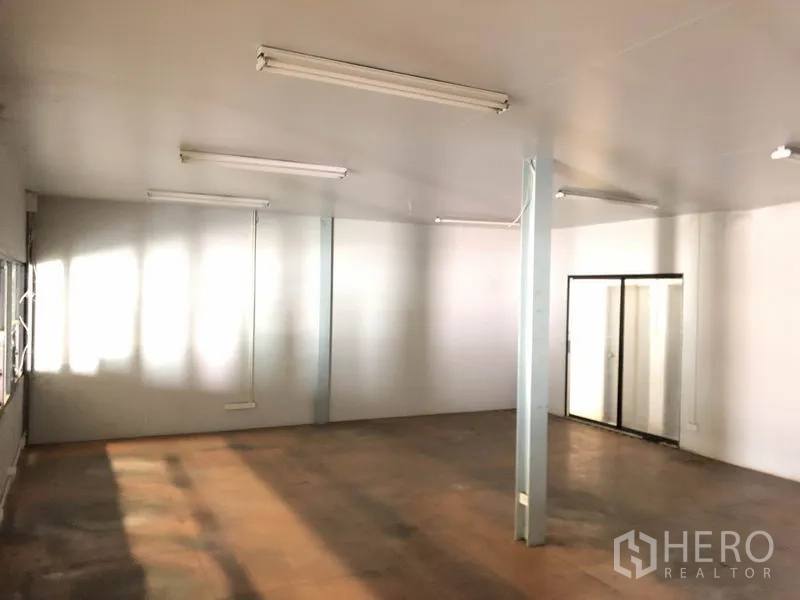 Warehouse for rent in Pathum Thani - Clean office room inside the warehouse with windows, fluorescent lights and a sliding glass door.