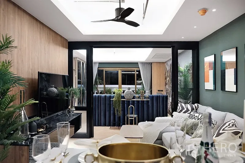 公寓 出租在Bang Rak, Bangkok - 从餐区望向客厅与电视柜，天花吊扇、蓝色吧台及大窗户。