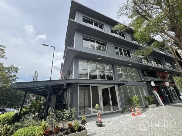 店屋 出租在Wang Thonglang, Bangkok - 灰色四层商用店屋外角度，落地玻璃立面、树木与铺装前庭。