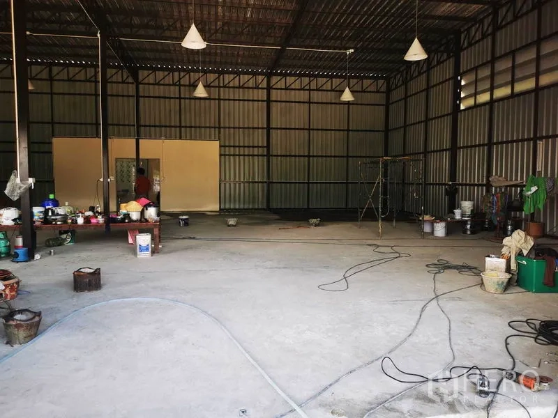 Warehouse for rent - Spacious warehouse floor with metal walls, pendant lights and a rear partitioned room.