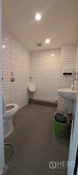 零售空间 出租在Bang Rak, Bangkok - 干净的卫生间，白色地铁砖墙，坐便器、小便池和洗手盆。