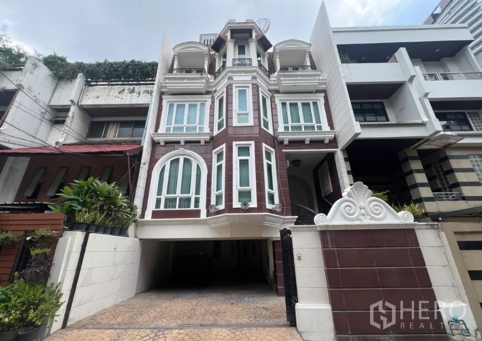 ทาวน์เฮาส์ ขายในWatthana, Bangkok - หน้าบ้านทาวน์เฮาส์หลายชั้น หน้าต่างโค้ง ทางรถและประตูรั้วในย่านวัฒนา