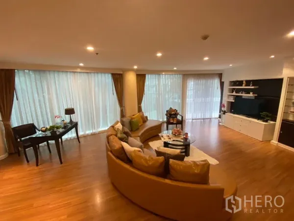 อพาร์ทเมนท์ ให้เช่าในWatthana, Bangkok - ห้องนั่งเล่นกว้าง โซฟาทรงโค้ง หน้าต่างสูงจรดเพดาน และชั้นวางทีวีบิลท์อิน