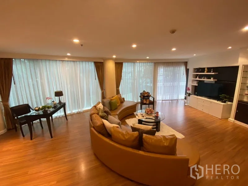 อพาร์ทเมนท์ ให้เช่าในWatthana, Bangkok - ห้องนั่งเล่นกว้าง โซฟาทรงโค้ง หน้าต่างสูงจรดเพดาน และชั้นวางทีวีบิลท์อิน