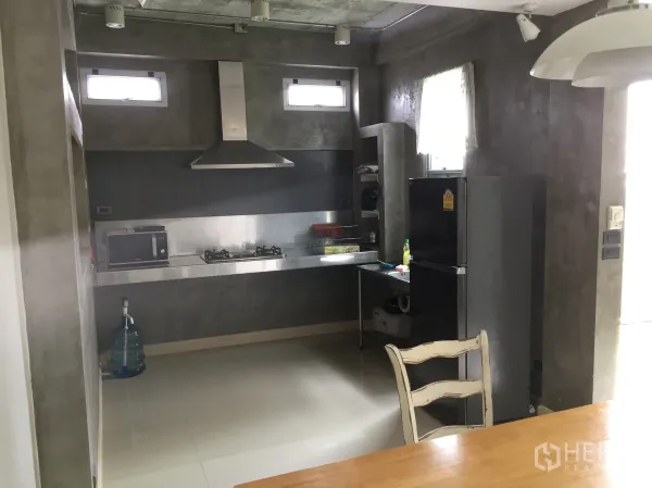 联排别墅 出租在Din Daeng, Bangkok - 混凝土风格厨房，配不锈钢台面、燃气灶、排烟机、冰箱与采光窗。