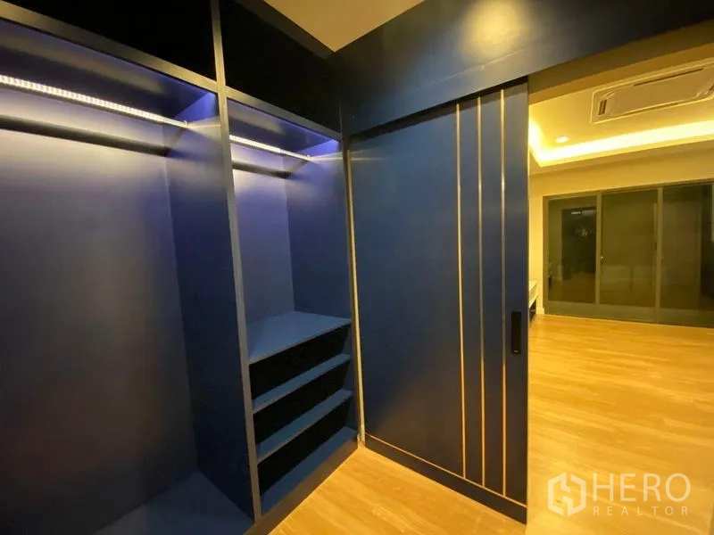 Detached House for rent - Walk-in closet with deep blue cabinetry and sliding door beside warm wood floors.