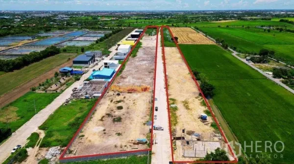 Land for sale in Bang Bua Thong, Nonthaburi - Top-down view of expansive industrial land parcels marked with red borders, drainage canal along the edge, and open sky.