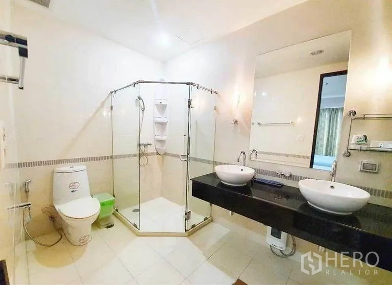 公寓 出租在Ratchathewi, Bangkok - 洁净浴室，转角玻璃淋浴间，黑色台面双盆与坐便器。