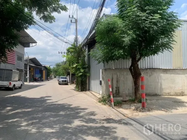 คลังสินค้า ให้เช่าในBang Kapi, Bangkok - ถนนคอนกรีตกว้างในย่านอุตสาหกรรมเบา มีโกดังเรียงราย ต้นไม้ข้างทางและสายไฟเหนือศีรษะ