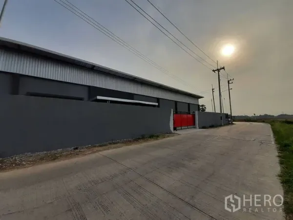 คลังสินค้า ให้เช่าในLam Luk Ka, Pathum Thani - มุมมองถนนคอนกรีตหน้าทรัพย์ กำแพงโกดังและประตูสีแดง