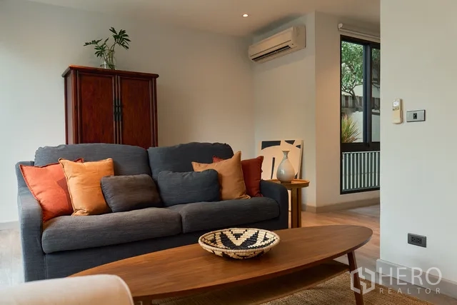 联排别墅 出租在Watthana, Bangkok - 客厅一角，空调、窗户与木柜在沙发旁。