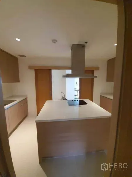 公寓 出租或出售在Sathon, Bangkok - 封闭式现代厨房，带中岛电炉、抽油烟机与浅木色橱柜。