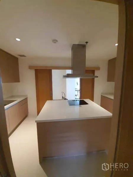 公寓 出租或出售在Sathon, Bangkok - 封闭式现代厨房，带中岛电炉、抽油烟机与浅木色橱柜。