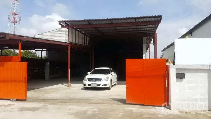 คลังสินค้า ขายในLam Luk Ka, Pathum Thani - ด้านหน้าโกดัง ประตูสไลด์สีส้ม ลานคอนกรีตกว้าง มีหลังคาคลุมจุดขนถ่าย โครงสร้างเหล็ก